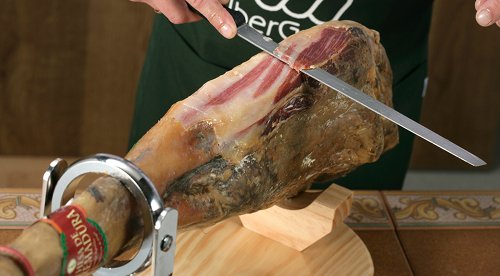 Primer plano de un cortador cortando un jamón ibérico