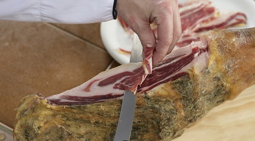 Primer plano de un cortador cortando una paleta ibérica