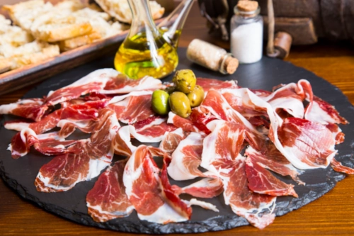 Lonchas de jamón ibérico, aceitunas, aceitera, salero