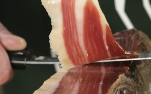 Primer plano de un corte de jamón ibérico de bellota con cuchillo jamonero