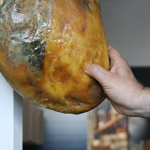 Primer plano de pulgar hundiéndose en la grasa de un jamón ibérico